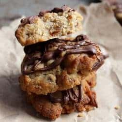 A stack of cookies filled with dates and drizzled with chocolate sitting on paper