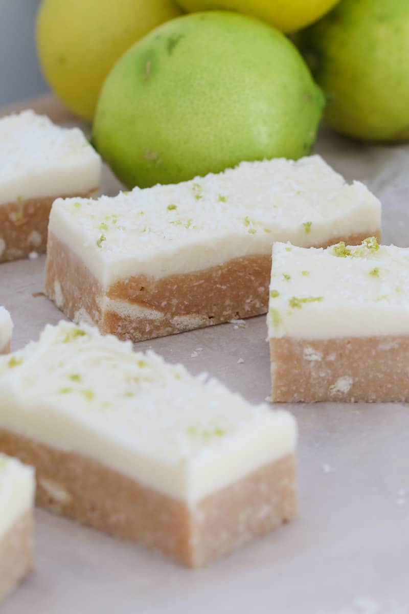 Pieces of slice with white icing in front of fresh limes