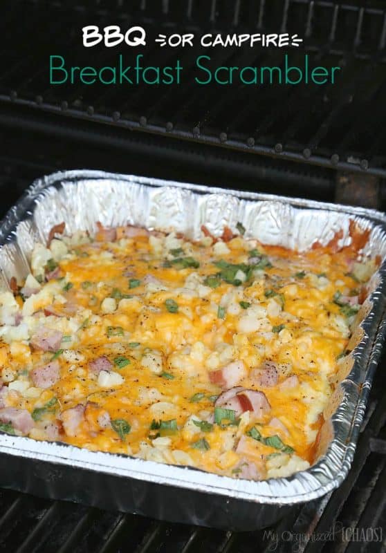 A breakfast bake of scrambled eggs, ham, spring onions and cheese being cooked in a foil tray on a camp BBQ. 