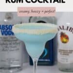 A creamy blue cocktail in a glass rimmed with white chocolate and coconut.