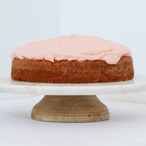 A cake with pink icing on a round cake tray