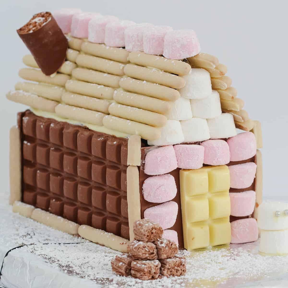 A super easy Chocolate Christmas House that makes an absolute showstopper of a table centrepiece! Use your favourite chocolates to decorate!