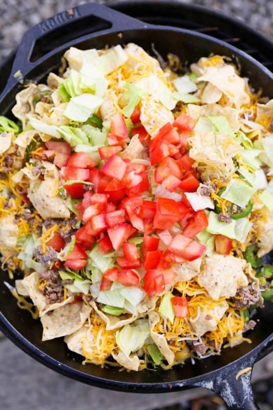 A bowl of nachos with tortillas, fresh tomato, lettuce, cheese and minced meat. 