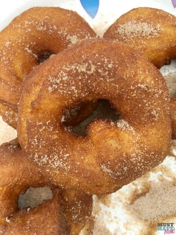 Homemade donuts being tossed in cinnamon sugar. 