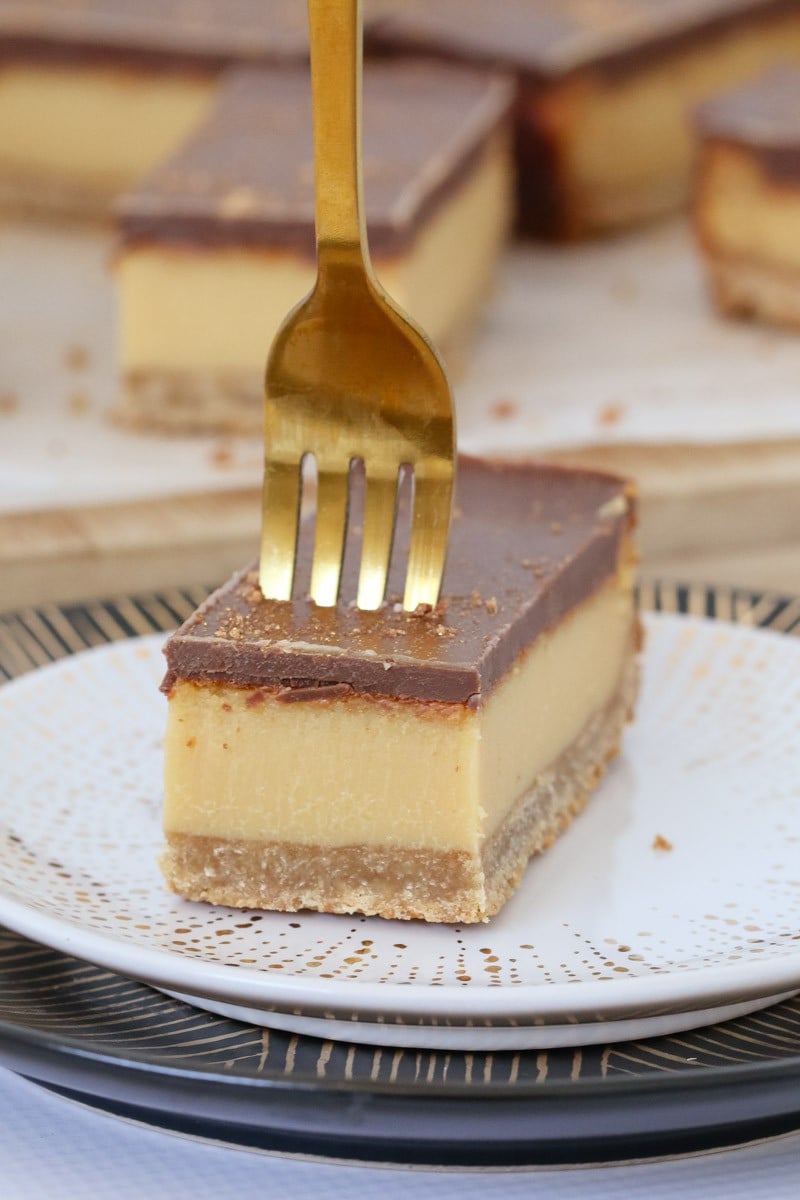 A gold fork being pressed into a piece of Millionaires shortbread.