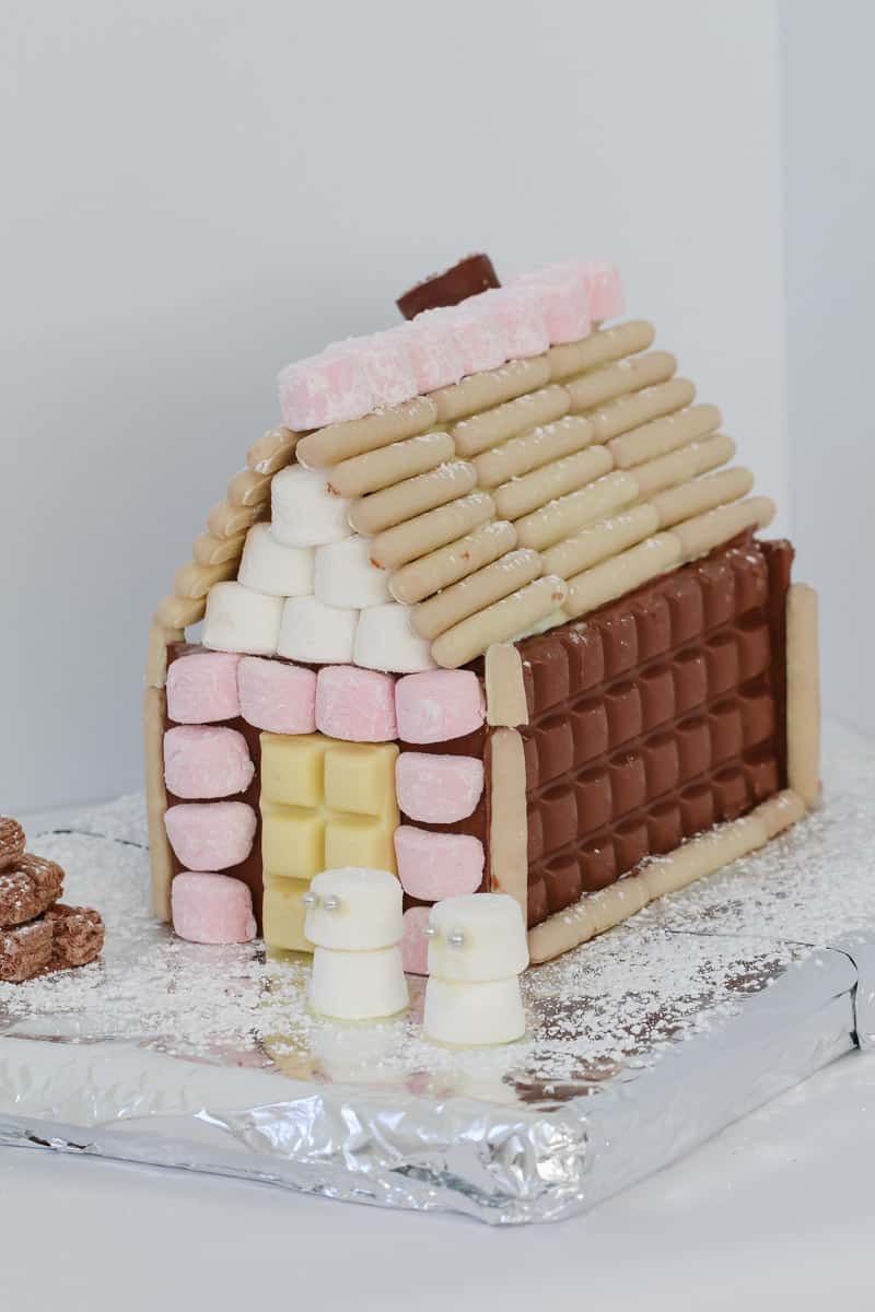 A gingerbread house, decorated with chocolate bars, chocolate logs and marshmallows
