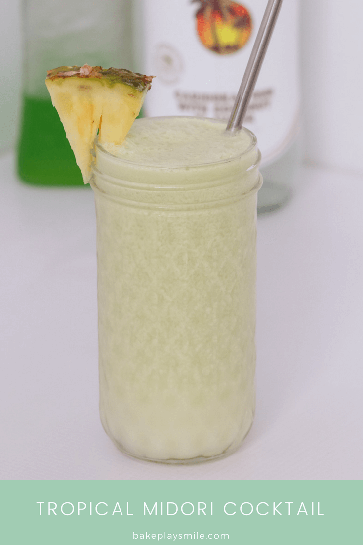 A textured glass jar filled with a cream coloured cocktail, a wedge of pineapple and a stainless straw