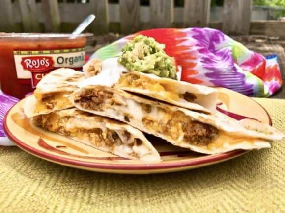 Quesadillas filled with meat and cheese on a picnic table outside. 