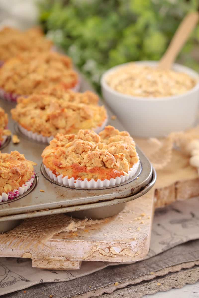 Apple muffins with a bowl of oats in the background. 