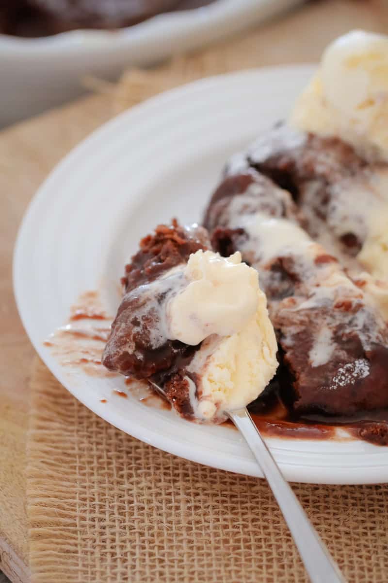 A spoonful of chocolate pudding with chocolate sauce and melting vanilla ice-cream. 