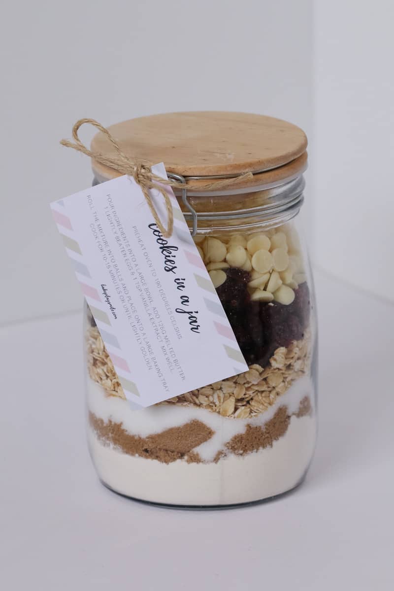 A glass jar with a label attached, filled with layers of dry ingredients