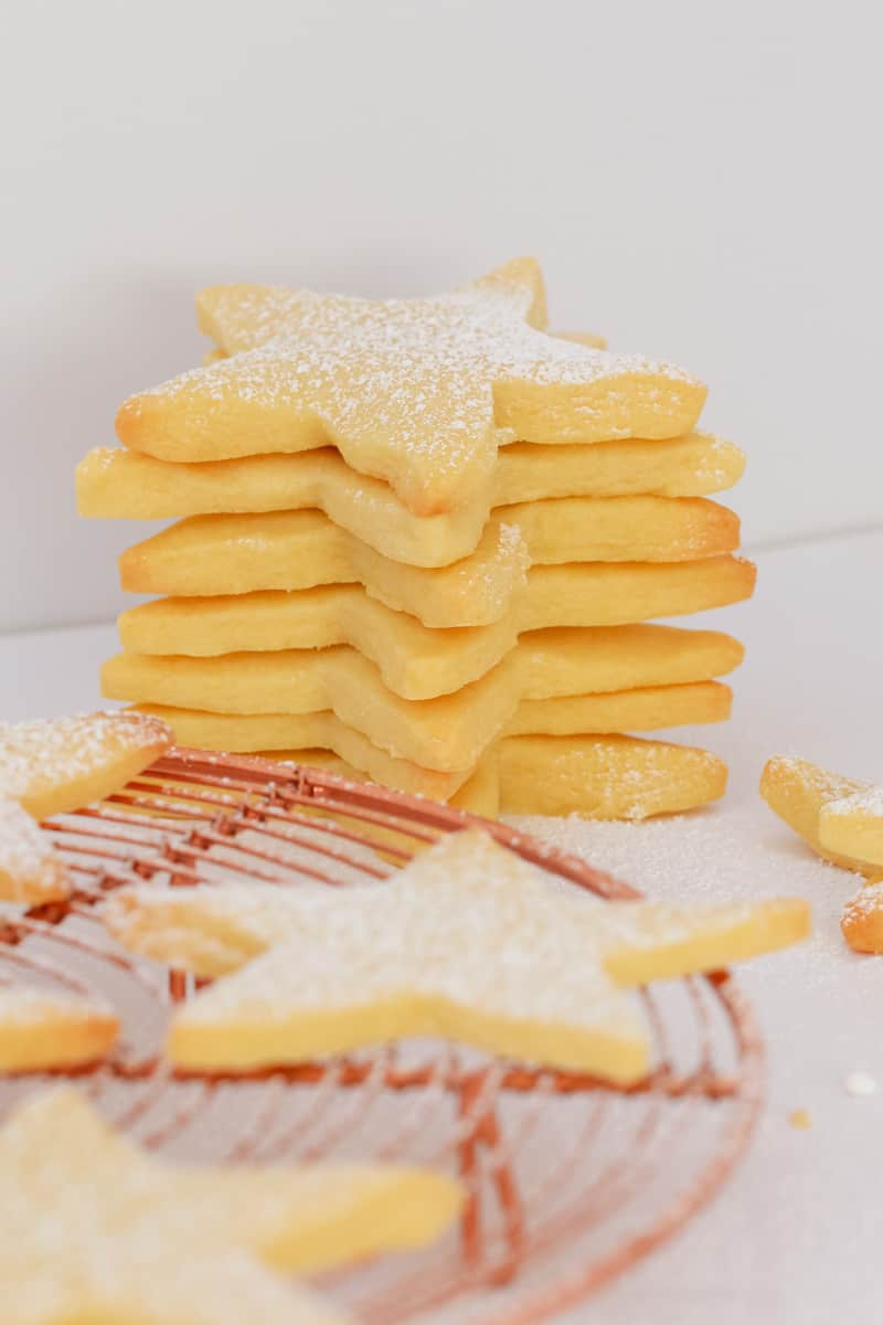A stack of shortbread star shaped cookies sprinkled with icing sugar. 