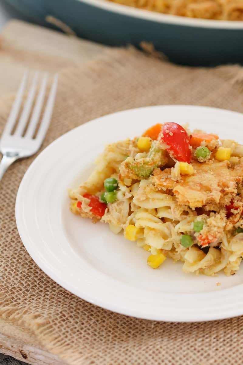 A white plate with a serve of a tuna, vegetable and pasta dish, on a table