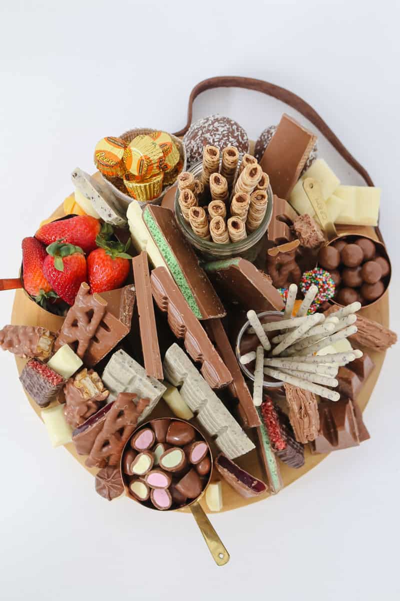 A platter with a selection of chocolate bars, chocolate treats, wafer rolls and fresh strawberries