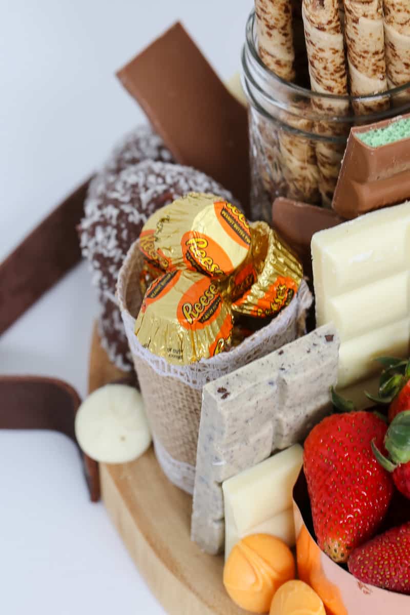 A variety of different chocolate treats and fresh strawberries on a wooden platter