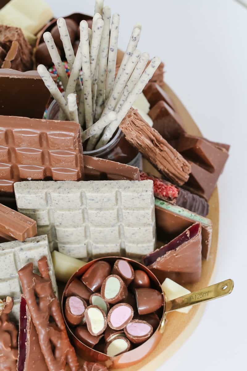 A close up of a wooden platter of various chocolate bars and chocolate sweets
