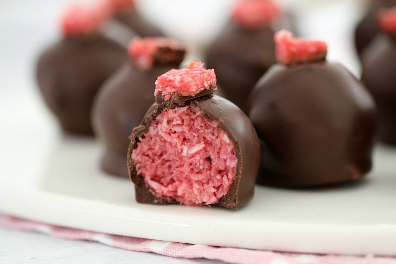 A plate of chocolate covered balls, with one cut to show a Cherry Ripe filling