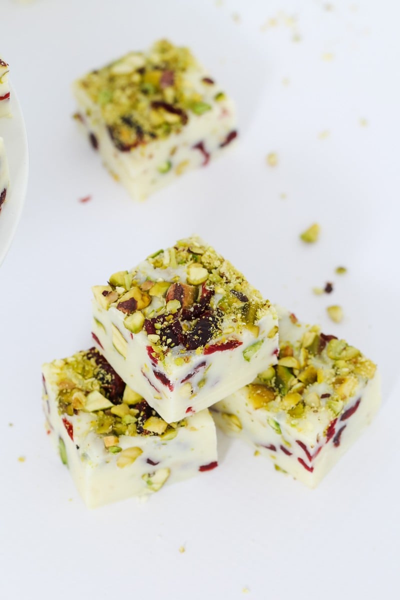 Pieces of a white chocolate fudge filled with cranberries and pistachio on a plate