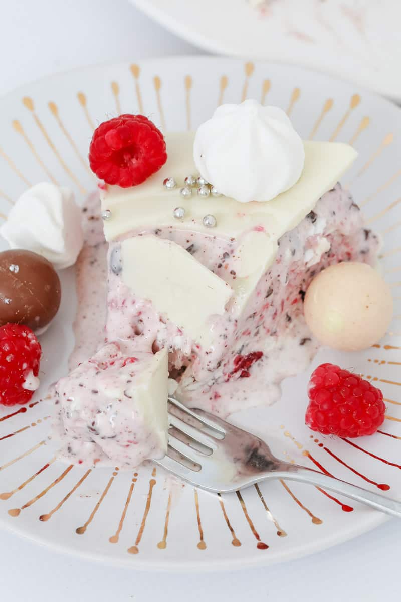 A serve of a pink raspberry and meringue ice-cream on a plate with white Ice Magic on top