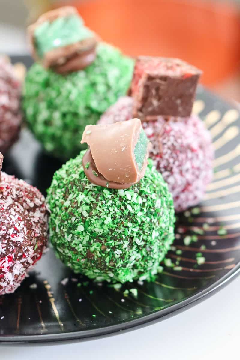 Coconut coated balls, decorated with pieces of Peppermint Crisp, on a black plate
