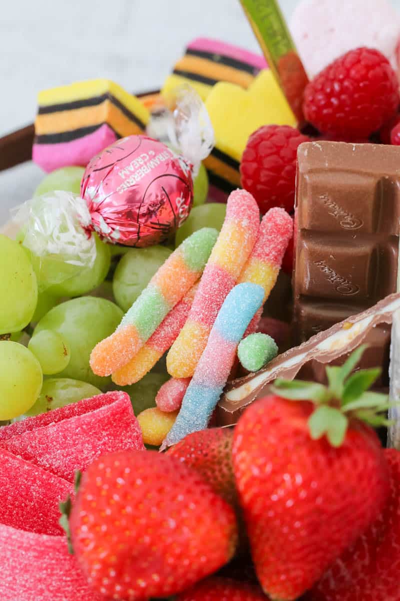A close up of chocolate pieces, grapes, strawberries and lollies