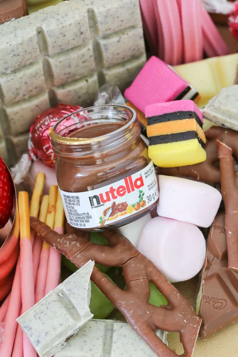 A close up of assorted chocolate pieces, a jar of chocolate hazelnut spread and lollies
