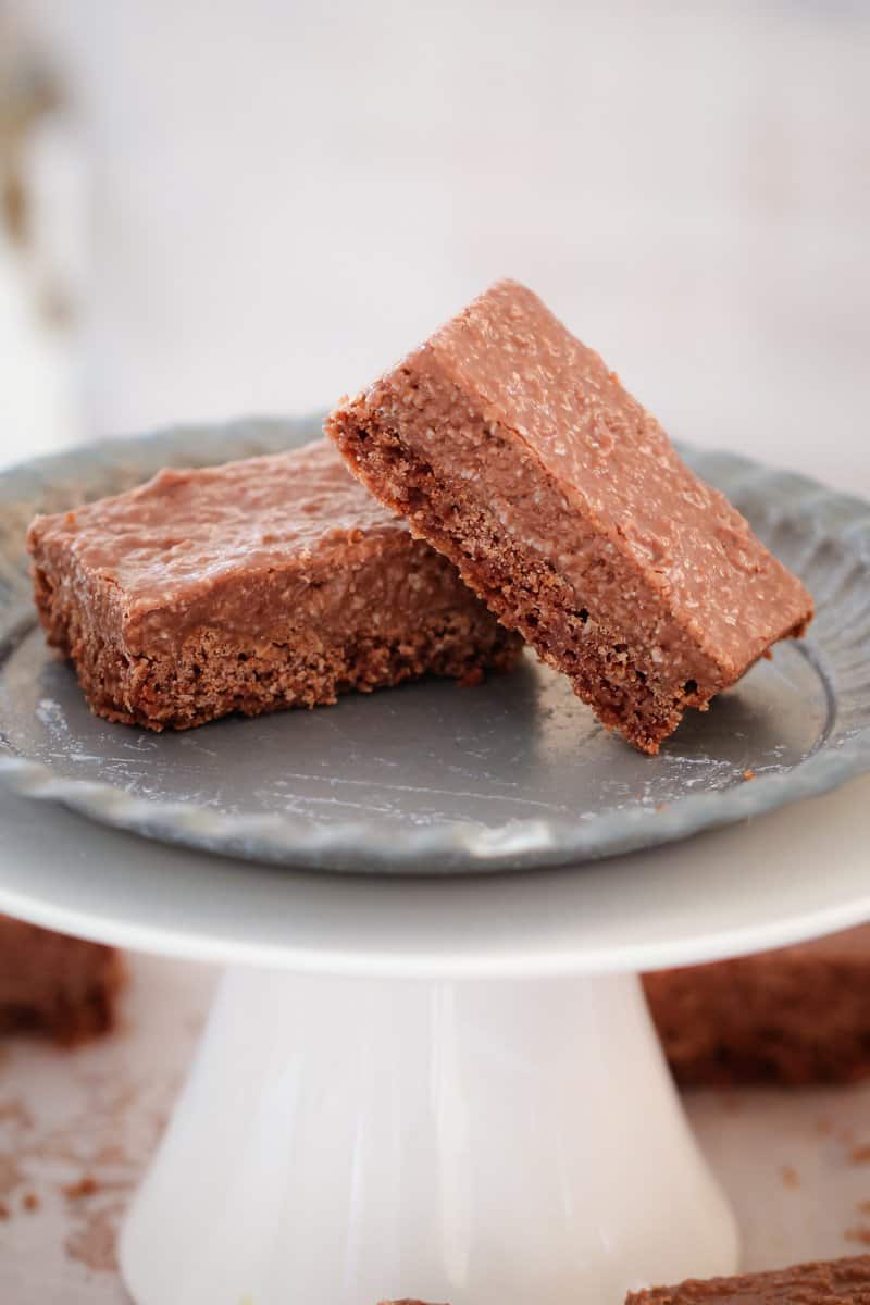 Two pieces of a chocolate coconut slice on a grey plate