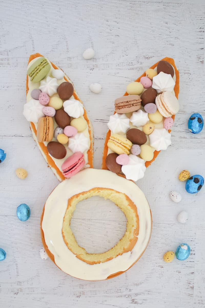 Sponge cake bunny ears decorated with macarons, easter eggs, meringues and chocolate. 