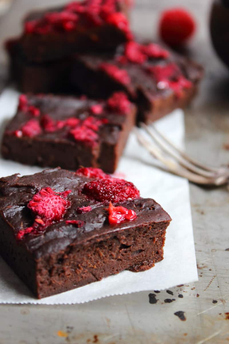 A piece of chocolate brownie with raspberries on top. 