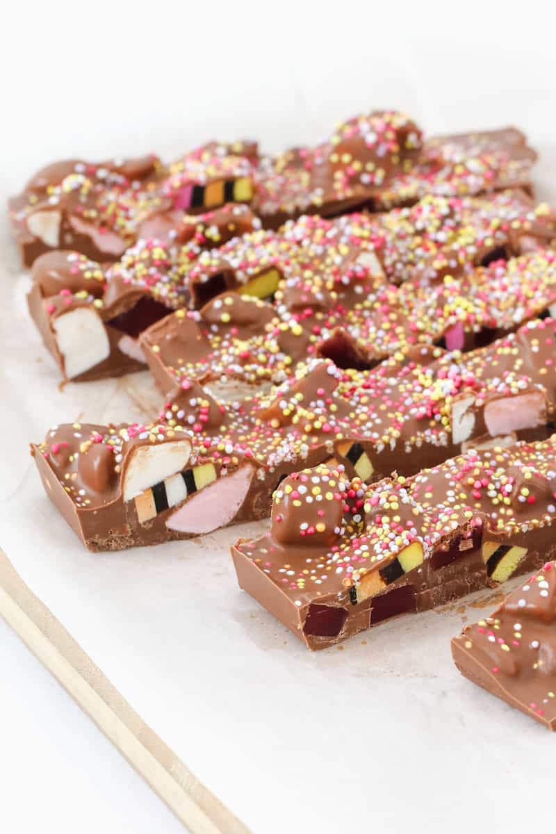 Bright and colourful rocky road being cut into slices on a chopping board. 