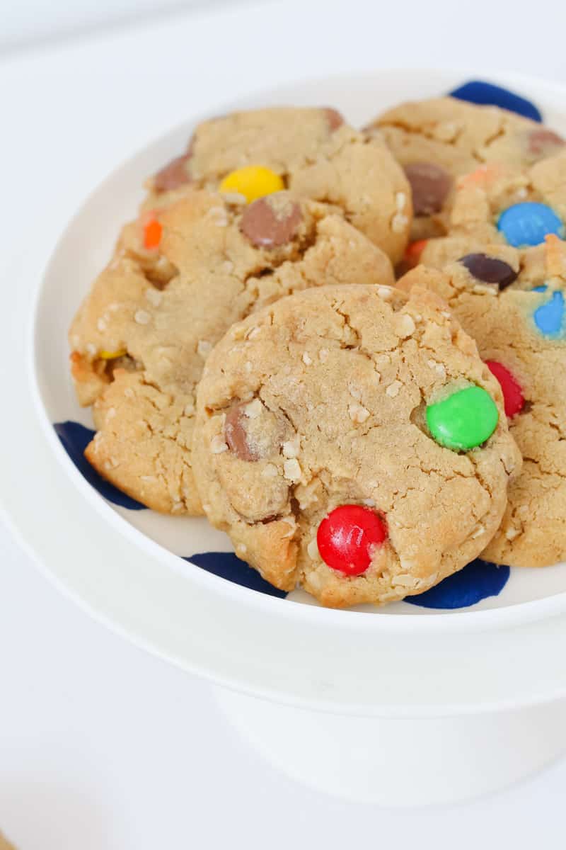 A white and blue plate of peanut butter cookies with oats, chocolate chips and M&Ms.