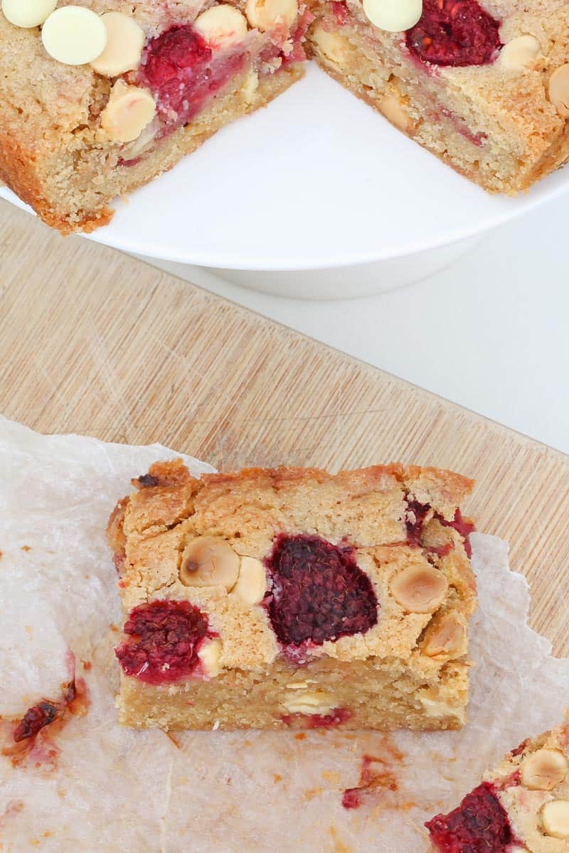 Raspberries and white chocolate chunks in a baked slice. 