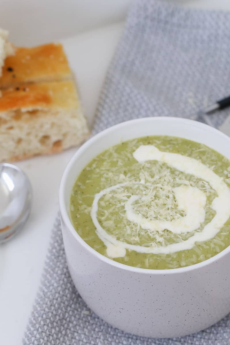 Parmesan cheese and cream on top of a green vegetable soup. 