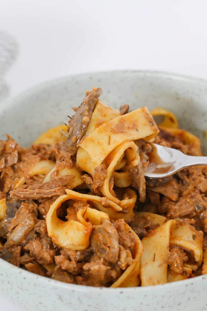 A forkful of beef stroganoff cooked in the slow cooker with pasta.