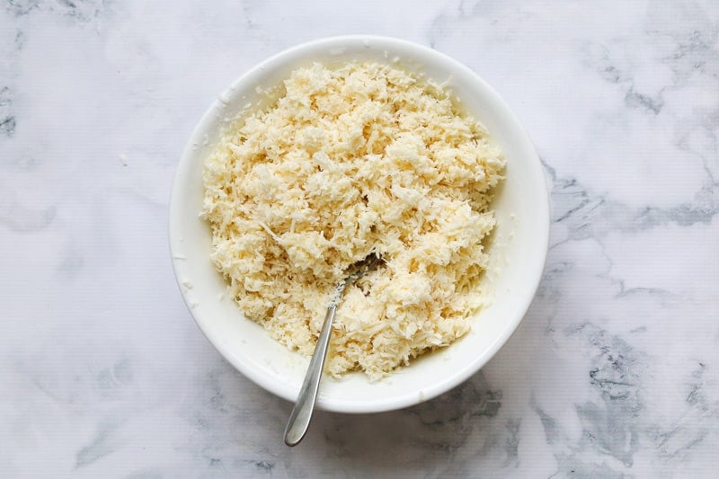 A bowl filled with shredded coconut and sweetened condensed milk.