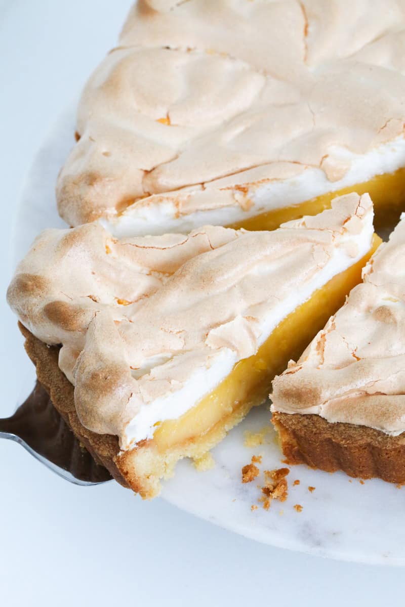 A cake slice removing a piece of lemon meringue pie.