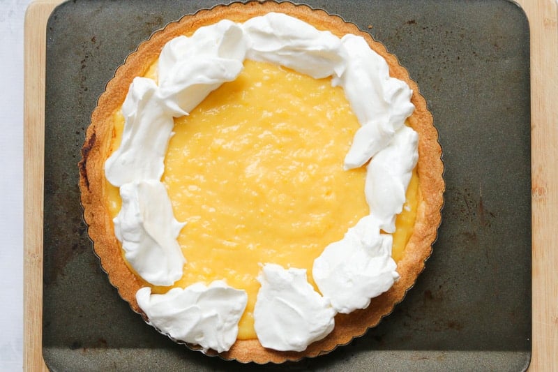 Meringue being added to the outside of a lemon tart.