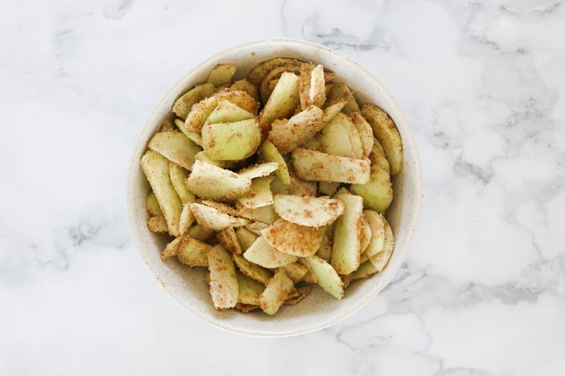 A bowl of apple slices coated in sugar and spices. 