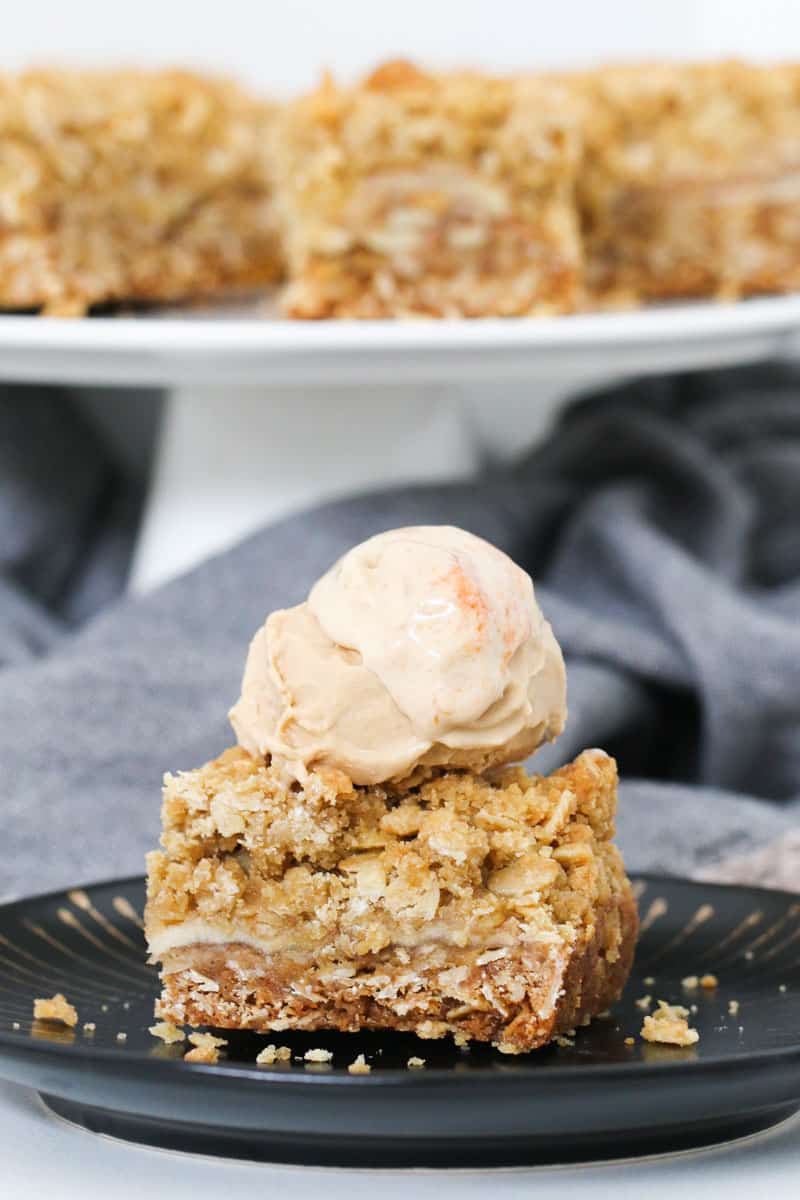 A scoop of ice-cream on top of an apple crumble dessert.