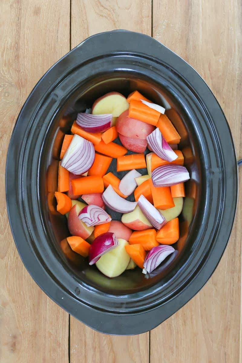 Vegetables in the base of a crock pot. 