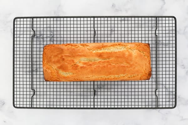A baked lemon and yoghurt loaf cooling on a wire rack. 