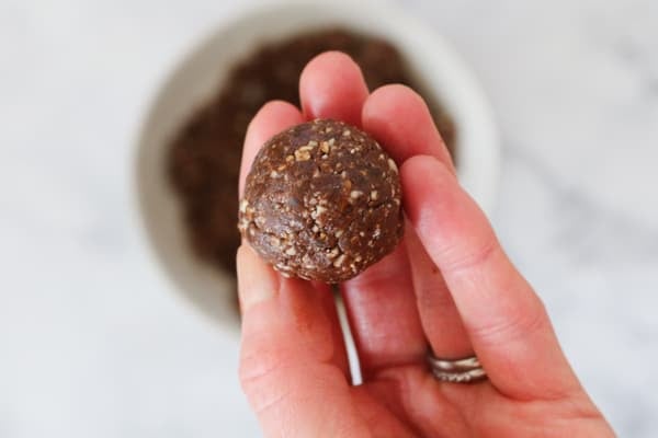 A hand holding a round protein bliss ball.