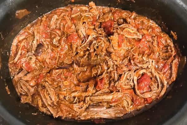 Shredded beef in a tomato sauce in a slow cooker.