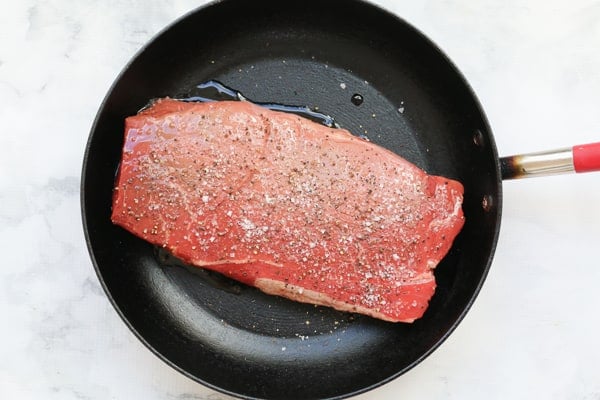 A piece of raw beef in a frying pan.