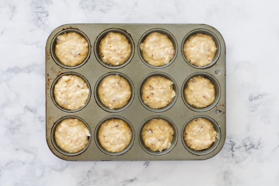 A muffin tray filled with sweet muffin mixture. 