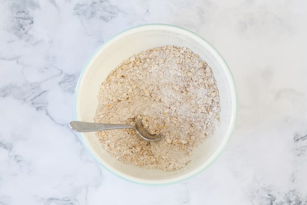 A bowl filled with oats, flour and sugar. 