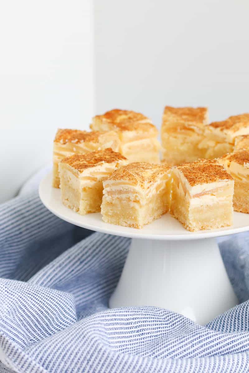 Pieces of slice layered with apple, sour cream and cinnamon on a cake plate. 