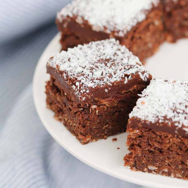 Pieces of chocolate coconut slice on a white plate.