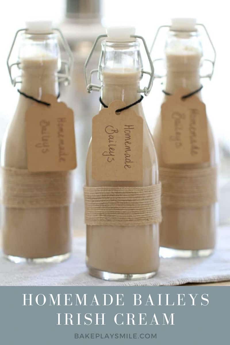 Small bottles filled with Homemade Baileys with handwritten labels tied around the neck of the bottles