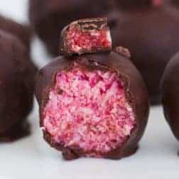 A half-eaten Cherry Ripe Ball covered in dark chocolate.